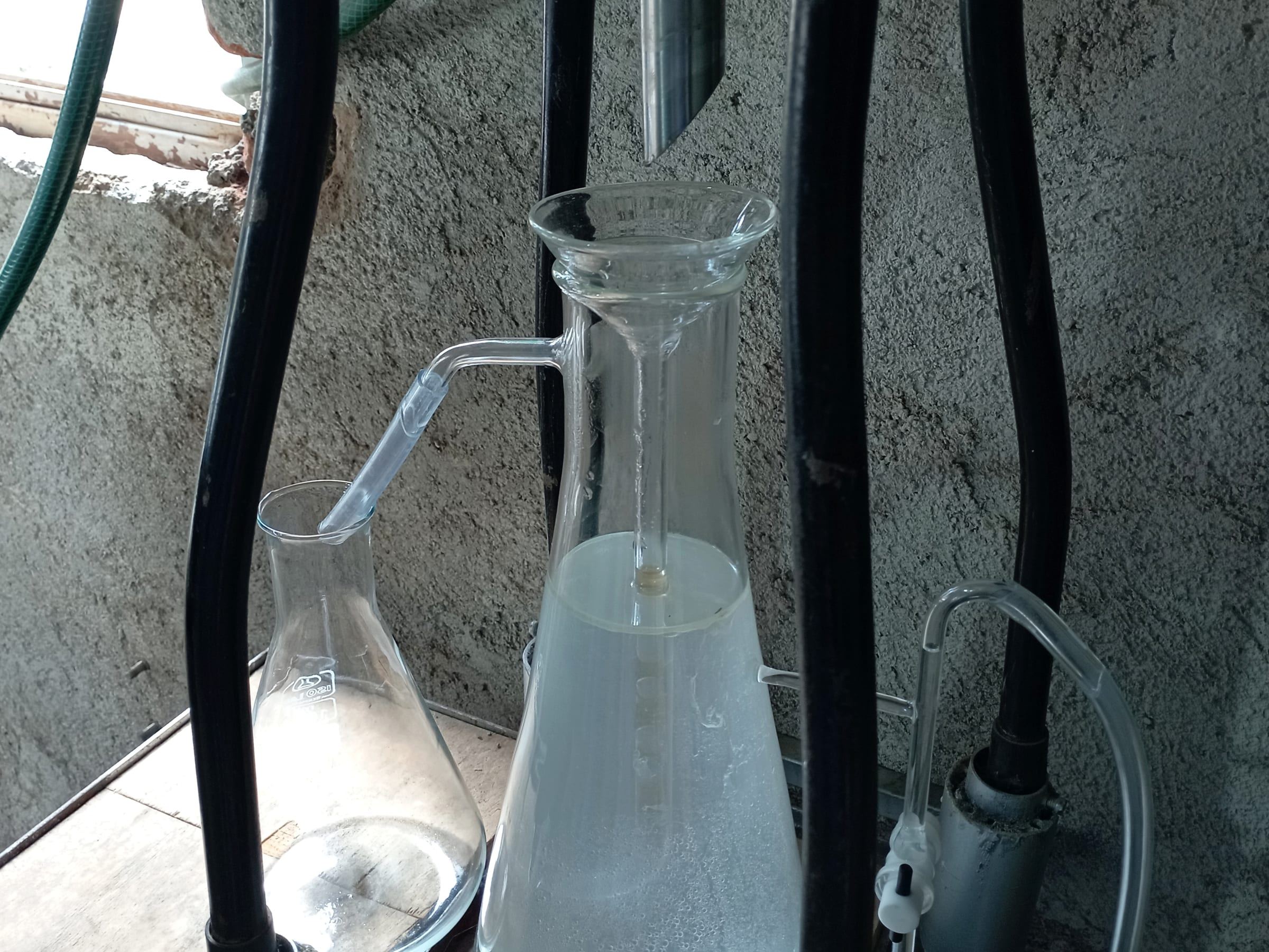 Laboratory glassware for distillation: a flask collecting condensate beside a receiver, with tubing